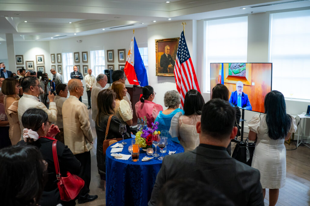 Distinguished guests watch attentively as Secretary of Foreign Affairs Enrique A. Manalo delivers his video message for the Filipino community.