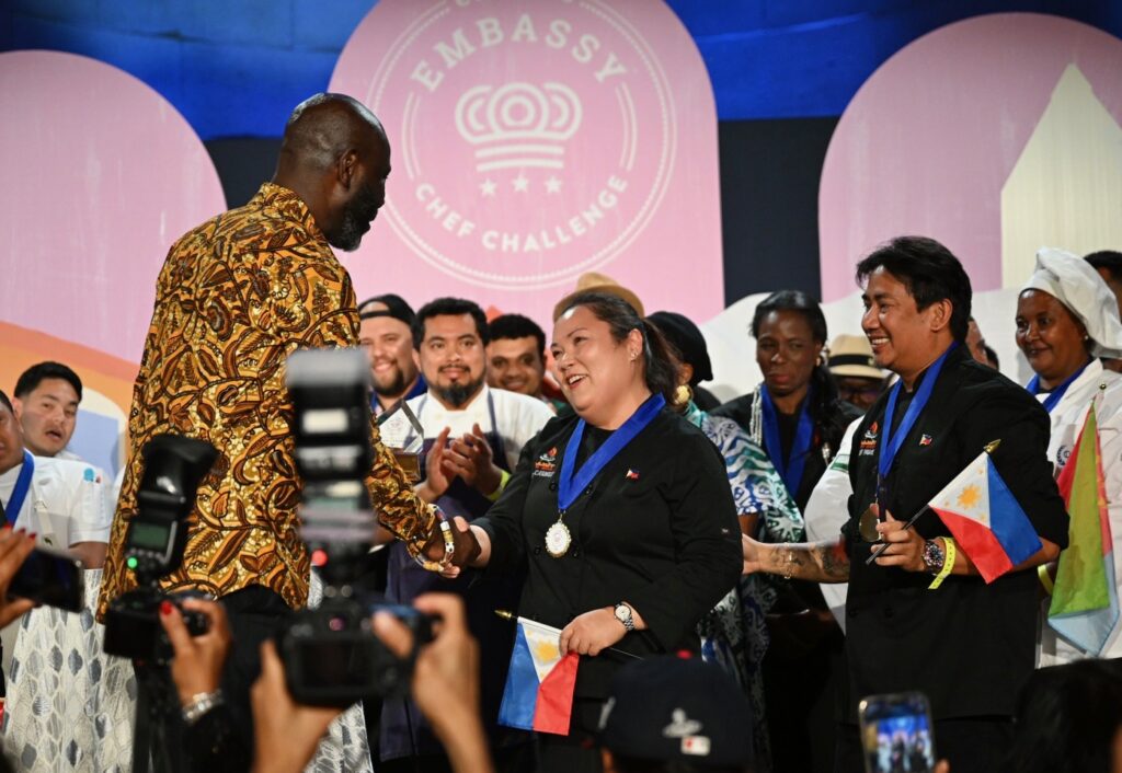 Chefs Paolo Peñalosa and Maria Carmel Tabligan proudly receive the People’s Choice Award from former ECC winner Chef Francis Otoo at the 2025 Embassy Chef Challenge, highlighting the distinctive tastes and culinary heritage of Filipino cuisine. (Photo credit: EventsDC)