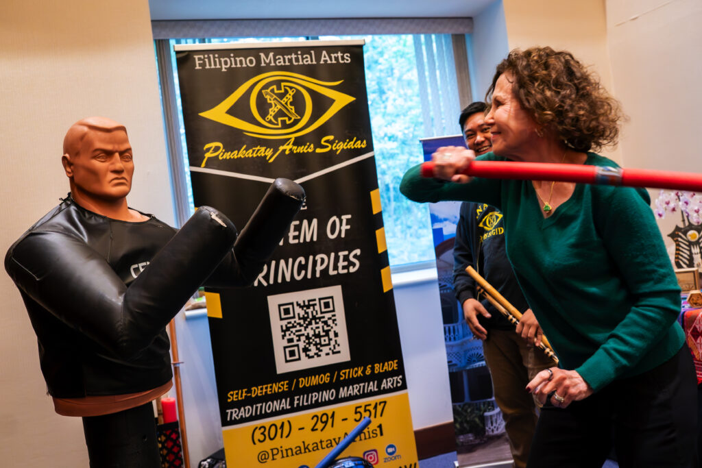 Energy and excitement fill the Philippine booth as a guest strikes a training dummy with their newly discovered Arnis ability.