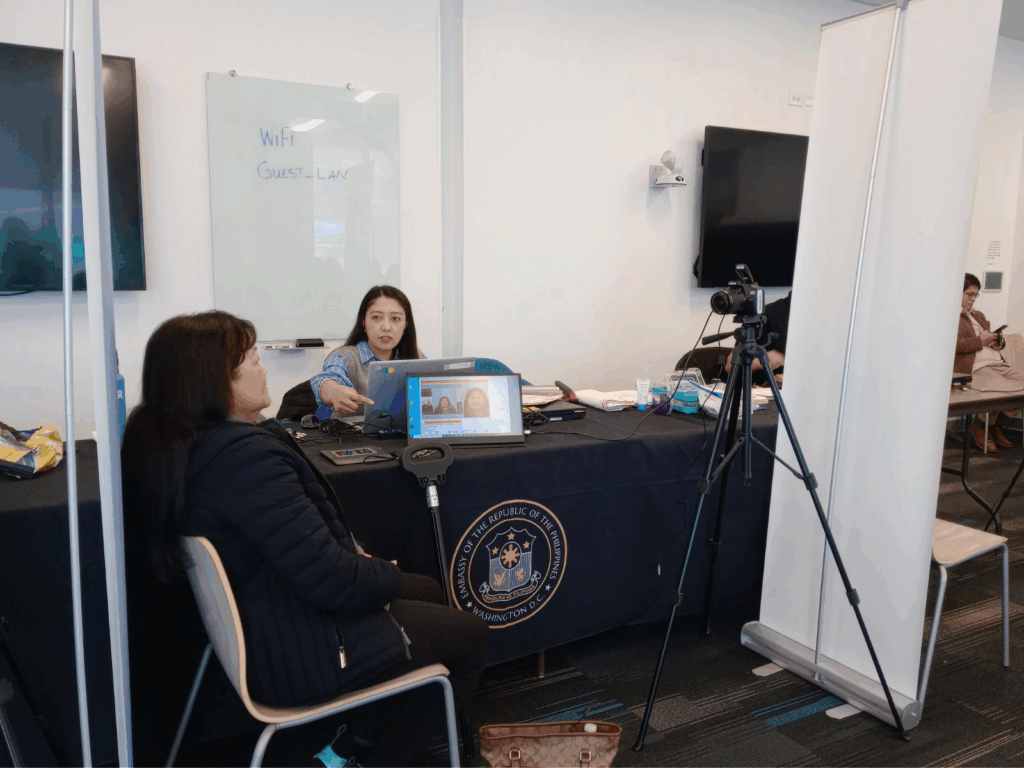 A member of the Philippine Embassy consular team captures the photo of a passport applicant.