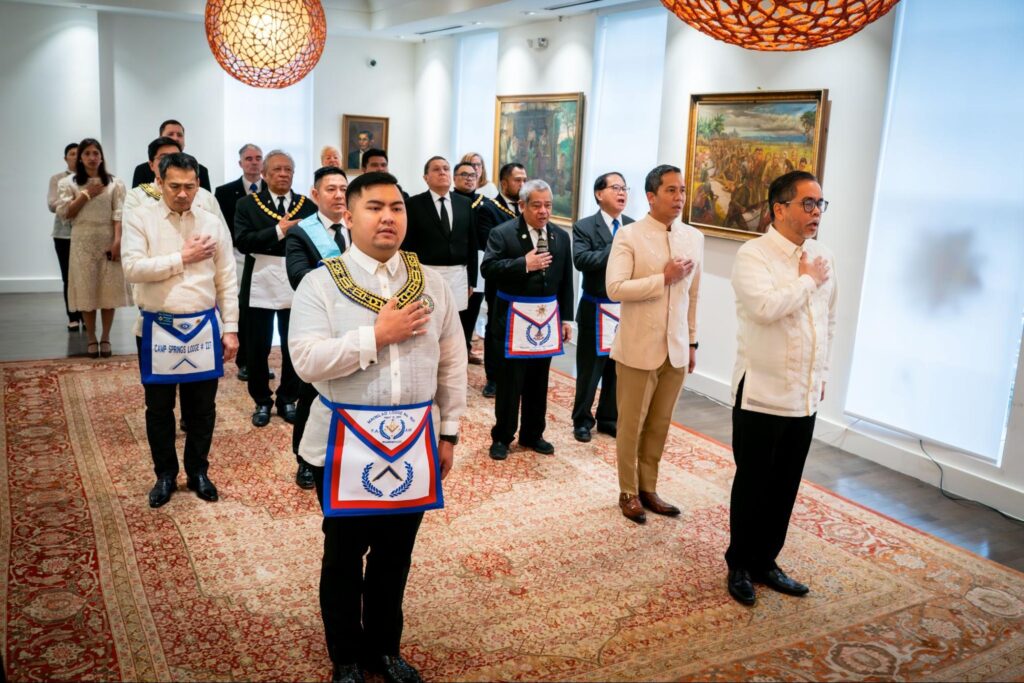 Guests from the Maynilad Lodge 1521, led by Lodge Master John David (front left), join Deputy Chief of Mission Jaime Ascalon, Jr. (front right), in solemn observance during the Philippine flag-raising ceremony marking Rizal Day. Also in attendance were Philippine Ambassador Gene Calonge (ret) and Col. Lee Sarpamones (PAF).
