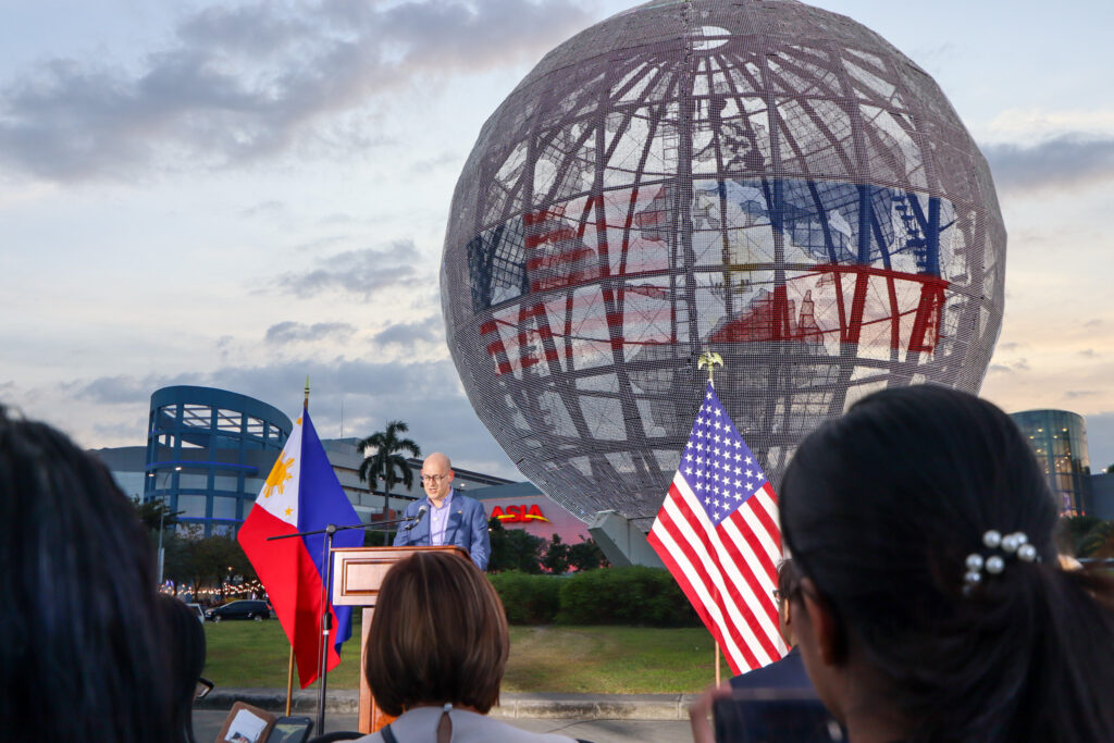 U.S. Embassy Charg&eacute; d&rsquo;Affaires a.i. Y. Robert Ewing addresses guests with the illuminated SM Mall of Asia Globe and the PH&ndash;U.S. 80th anniversary logo towering behind him. Photo Credit: DFA-OPD Johannes Adrian De Guia